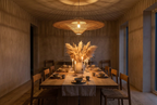 Wabi-Sabi wide rattan pendant light glowing at night above a dining table, casting soft shadows