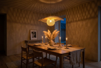 Hana Capeline bamboo pendant light glowing at night above a candlelit dining table